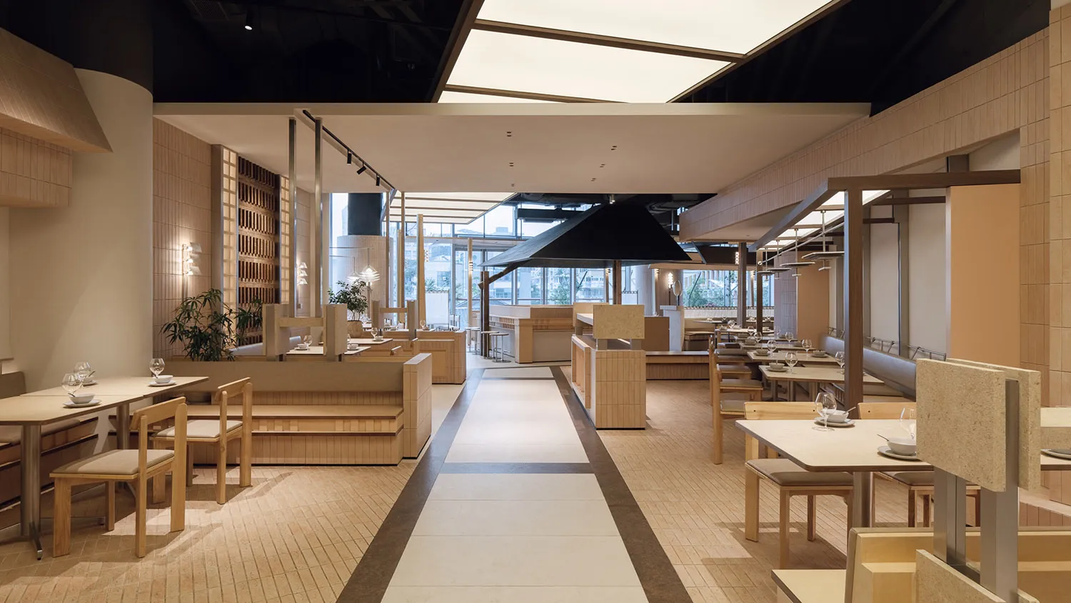 現代日式餐廳室內設計,設有淺木色長椅座位、石材桌面餐桌,以及由天窗照亮的中央長走道。