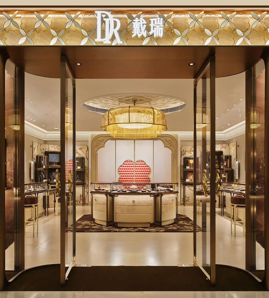 奢華珠寶店內部,大型金色編織流蘇吊燈、弧形奶油色展示櫃、精緻牆板與玻璃入口大門。