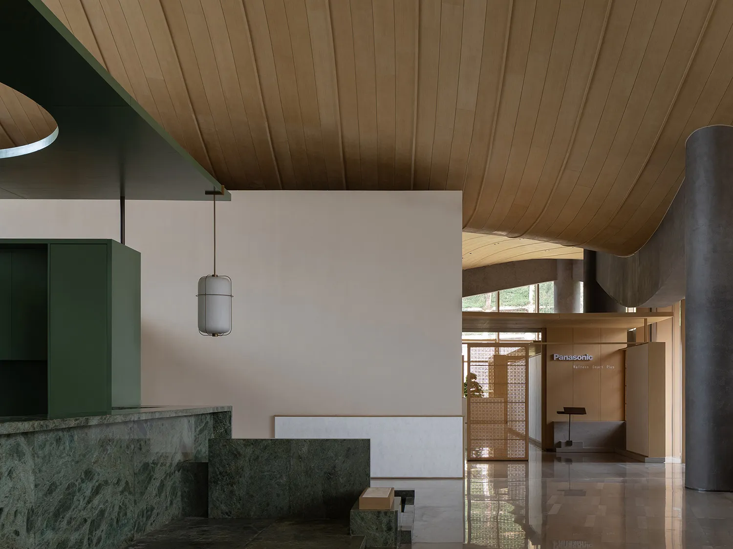 Modern commercial reception area featuring a dramatic curved wooden ceiling, green marble counter, and minimalist beige walls with pendant lighting.