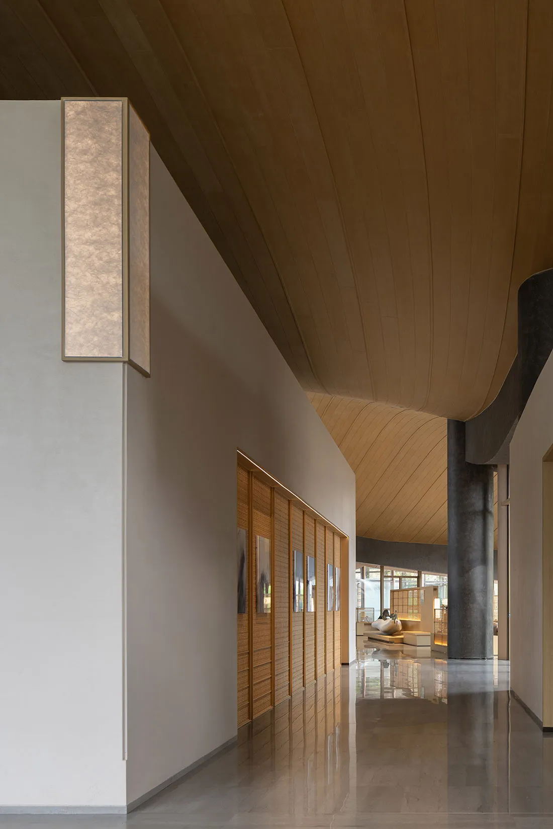 Modern minimalist hallway with curved wooden ceiling, textured stone walls, wooden slat doors, and reflective polished floors.
