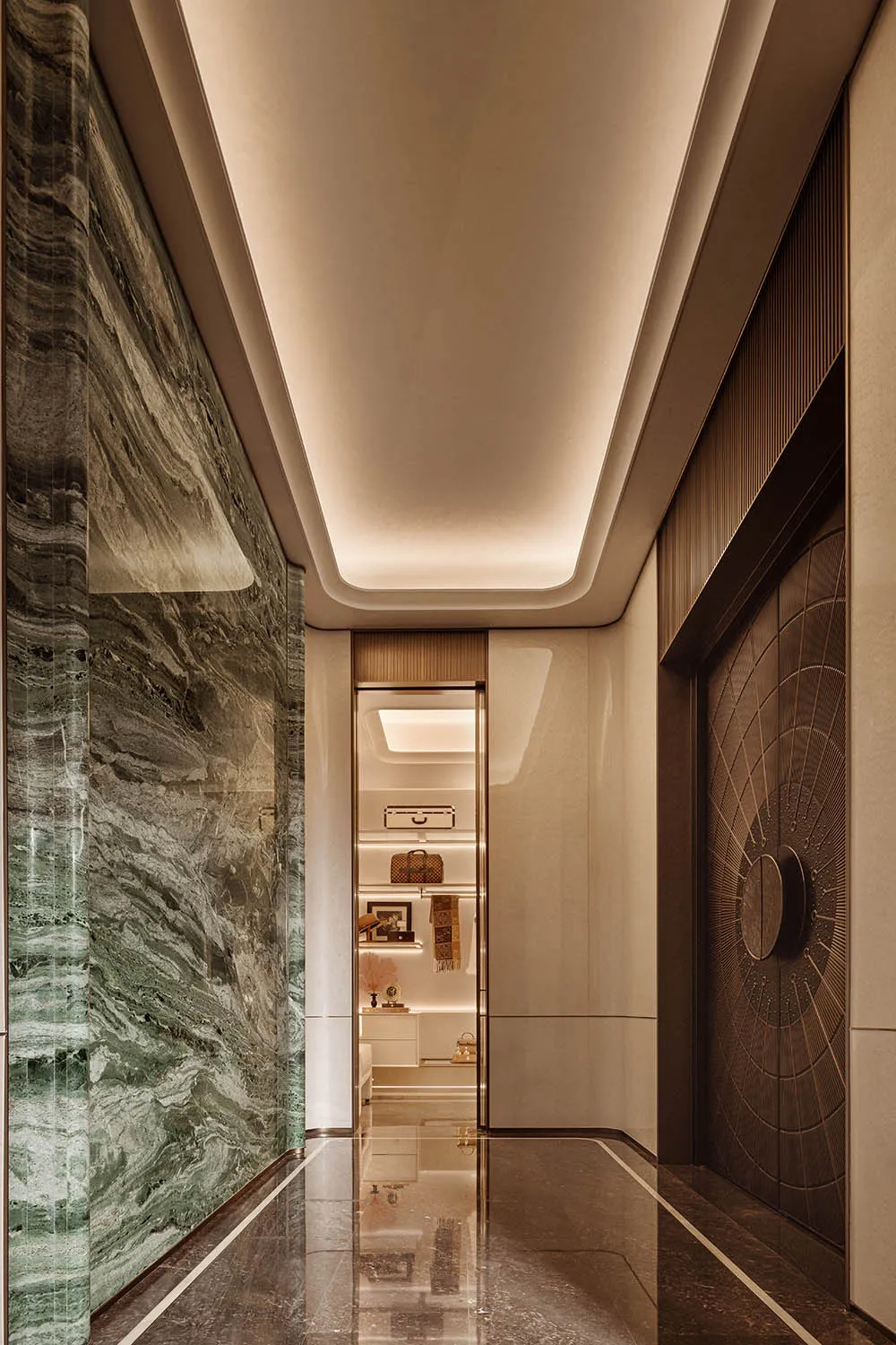 Modern luxury hallway with green marble wall, dark marble floor, recessed ceiling lighting, and a view into a walk-in closet.
