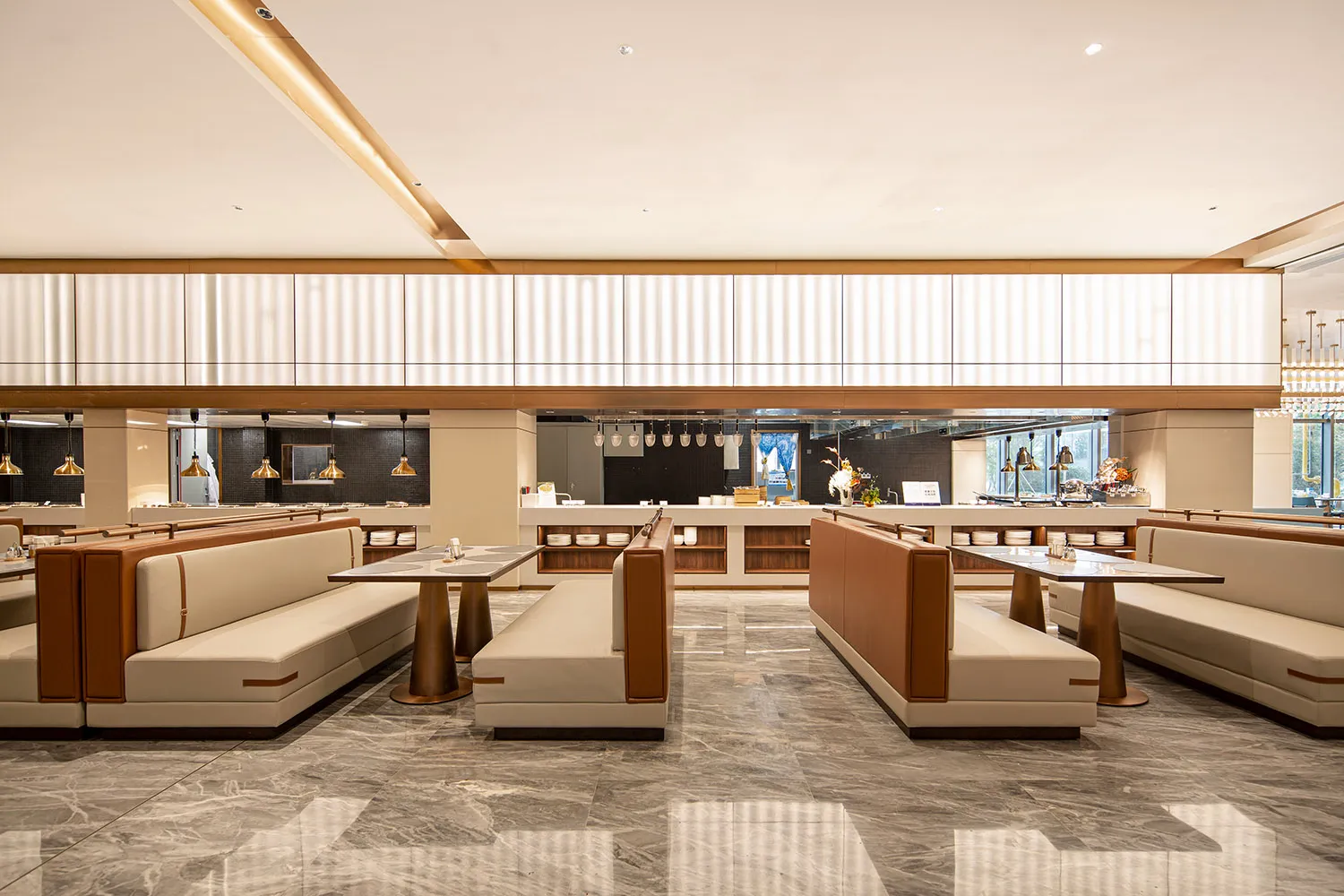 Modern elegant restaurant dining area with white and tan leather upholstered booths, marble tables, and polished grey marble floor.
