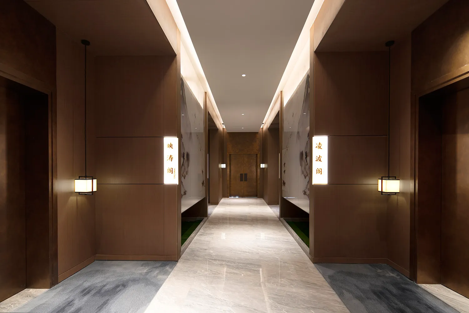 Long modern Chinese-style hotel corridor featuring dark wood paneling, large-format marble flooring, hanging lantern-style wall lights, and traditional ink painting wall panels.