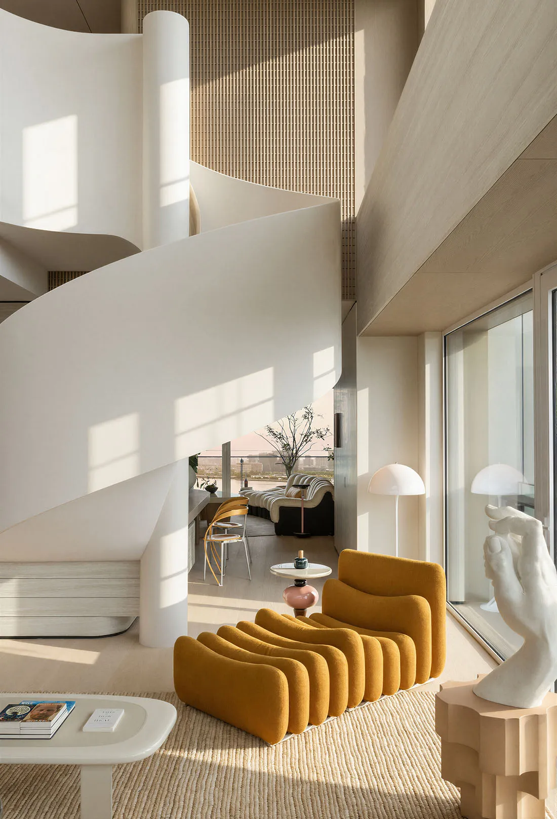 Modern minimalist living room featuring a dramatic white spiral staircase, mustard yellow curved modular sofa, light wood flooring, and large windows with harbor view.
