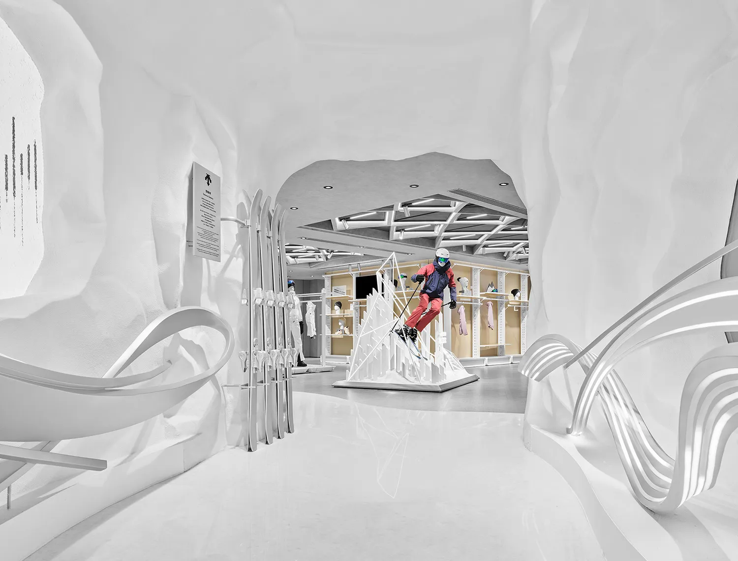 Modern ski retail store interior designed as a white snow cave with organic curved plaster walls, ski equipment display, and a mannequin skier in colorful winter gear.