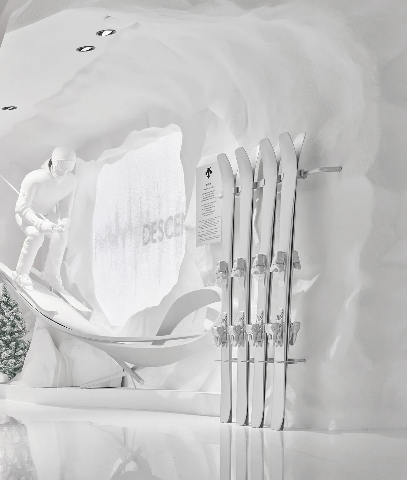 Modern all-white retail display featuring a ski rack with white skis, a skier snow sculpture on a ramp, and organic curved white cave walls with recessed lighting.