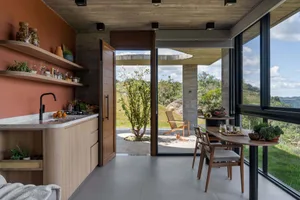 A modern kitchen with wooden finishes and a view of the outdoors through large windows.