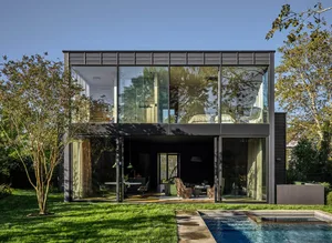 Contemporary single-level residential home with expansive glass windows and outdoor pool.