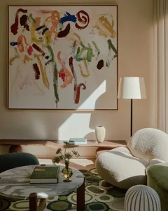 A living room with colorful abstract painting, comfortable seating, and wooden coffee table.