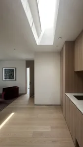 Modern minimalist hallway with skylight, wooden flooring, and sleek design elements.