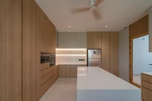 Modern minimalist kitchen featuring wooden cabinets, white countertops, and integrated appliances.