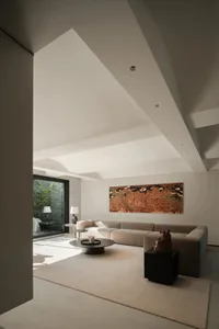 A modern, minimalist living room featuring a large cotton-couch and a coffee table with sculptures.