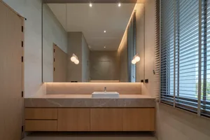 Modern bathroom with marble countertop and sink, illuminated by warm lighting.