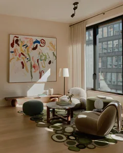 A modern living room with taupe walls, a marble coffee table, and colorful abstract art.