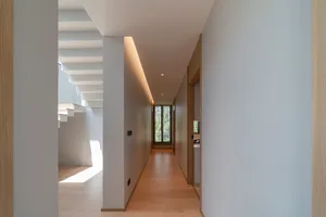 A modern minimalist hallway with wooden floors and white walls