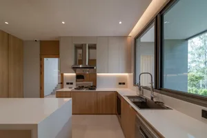Modern residential kitchen with white countertops and wooden cabinets.