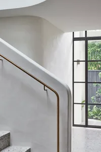 Industrial interior image showcasing concrete staircase with brass handrail.