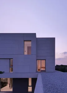A minimalist house with concrete exterior materials and large windows.