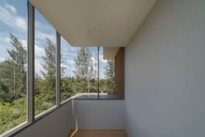 Modern minimalist interior with large glass door opening to outdoor area.