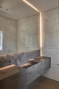 A minimalist modern bathroom with stone marble walls and a sink.