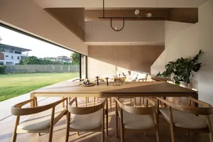 A modern dining room featuring wooden furniture and a large window overlooking a grassy lawn.
