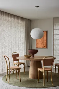 Modern dining room with a wooden table, chairs, and a round rug.