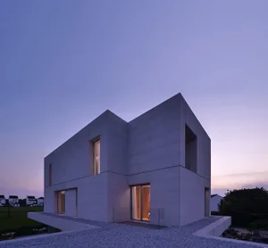 A minimalist, modern house with concrete walls and large windows.