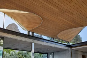 Modern indoor space with a wooden ceiling and concrete walls, featuring natural light and a mountain view.