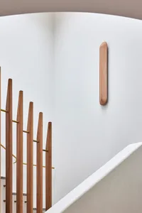 A minimalist interior design featuring a wooden staircase with a white railing.