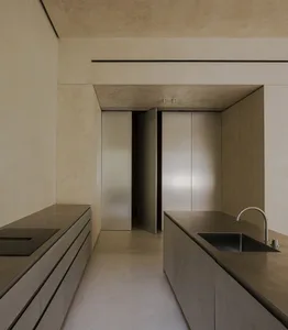 Modern, minimalist kitchen with concrete countertops and stainless steel appliances.