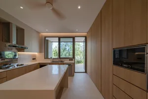 Modern kitchen with minimalist design, featuring wood cabinetry and a white countertop.