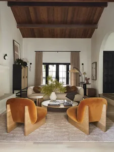 Modern living room featuring velvet chairs and wooden accents.