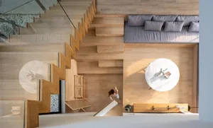 Modern living room featuring a circular coffee table, a sectional sofa, and a staircase with a glass railing.
