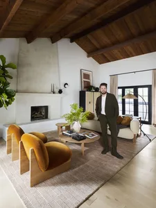 A modern living room with wooden furniture, a fireplace, and green plants.