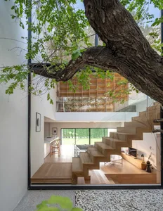 Modern living room featuring wooden stairs and large windows.