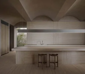 Modern minimalist kitchen with concrete walls and a long central island.