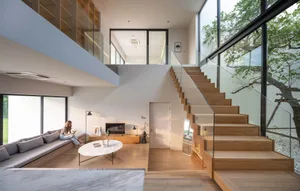 A modern, minimalist residential staircase with wooden steps and glass railings.