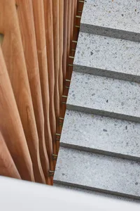 A photograph of a modern staircase with concrete steps and wooden railings.