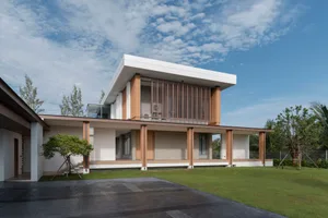 A modern villa with a rendered concrete exterior and large overhanging roof.