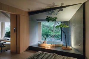 A minimalist bathroom with a ceramic bathtub surrounded by greenery and a tree, featuring modern design elements and natural 