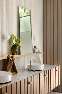 Modern minimalist bathroom with white walls, terrazzo tiles, and a sleek sink with a curved faucet.