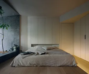 Minimalist bedroom with a wood floor, grey walls, and grey bedding.