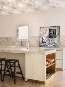 Modern kitchen with marble countertops and wooden stools.
