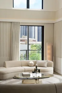 A minimalist living room featuring neutral-colored furniture and a large window with city views.