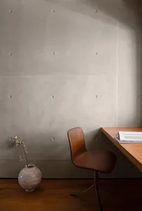 A minimalist workspace featuring a wooden frame and desk, with a brown chair and a small vase with a plant.