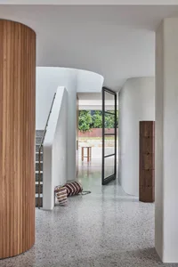 Modern design interior with concrete floors and walls, featuring a hallway with curved walls and stairs.
