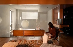 A modern living room with wood flooring, glass coffee table, and fabric seating.