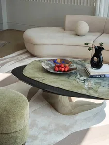 A modern marble coffee table with a black base and a vase with a black vase and glass on top.