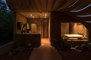 Modern minimalist residential space with glass walls and a view of a cave-like structure