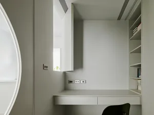 A modern minimalist home office with a floating desk, white walls, and a minimalist chair.